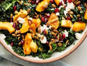 bright colored fall kale salad with berries, nuts and golden squash